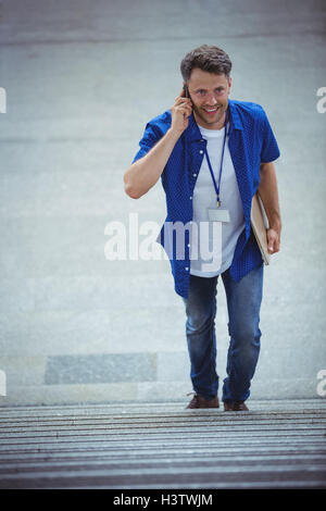 Handsome man walking on stairs while talking on mobile phone Stock Photo
