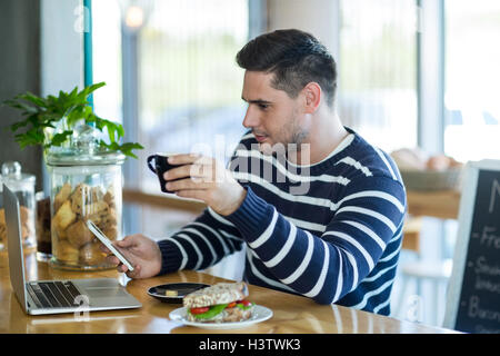 Man using a mobile phone while having cup of coffee Stock Photo