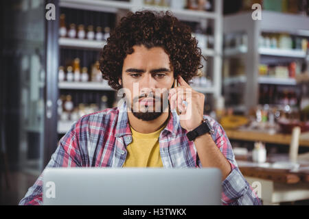 Man using laptop while talking on mobile phone Stock Photo