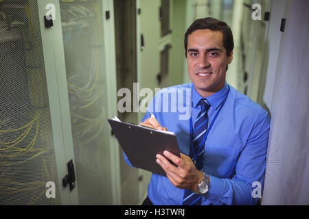 Technician maintaining record of rack mounted server on clipboard Stock Photo