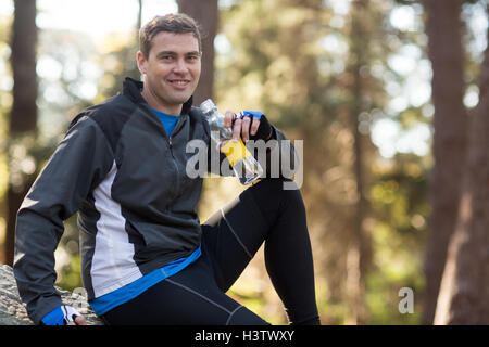 Male biker drinking water in forest Stock Photo