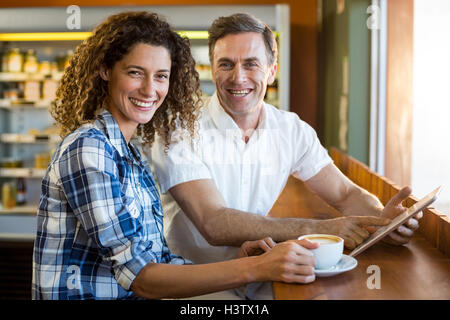 Portrait of happy couple using digital tablet in caf├⌐ Stock Photo