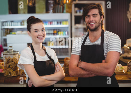 Waiter and waitress standing with arms crossed in cafe Stock Photo
