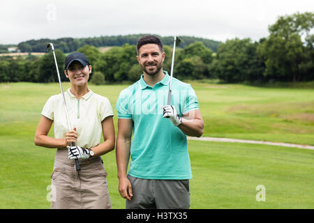 Couple standing with golf club in golf course Stock Photo