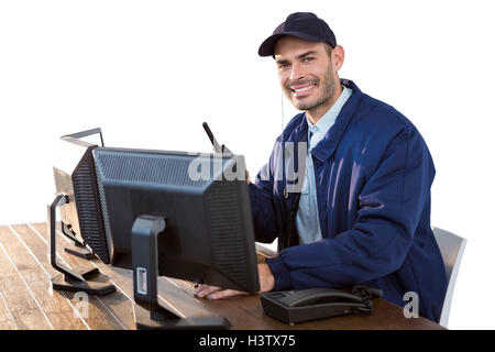 Happy Security officer talking on walkie-talkie while using computer Stock Photo