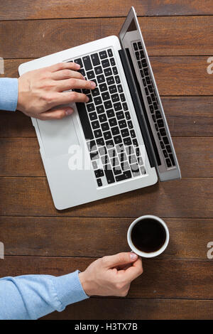 Man using laptop while having cup of coffee Stock Photo