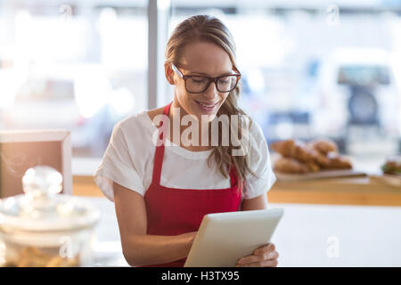 Waitress sitting at table and using digital tablet in caf├⌐ Stock Photo
