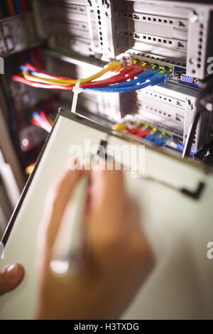 Technician maintaining record of rack mounted server on clipboard Stock Photo