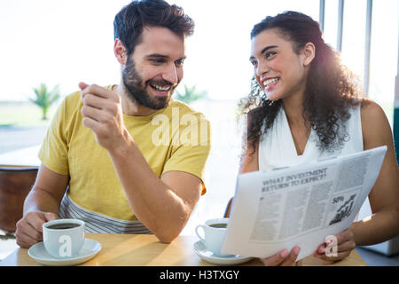 Couple reading newspaper while having coffee Stock Photo