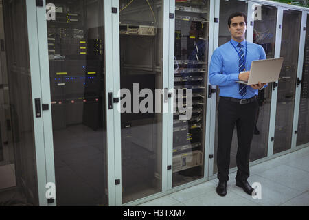 Technician using laptop while analyzing server Stock Photo