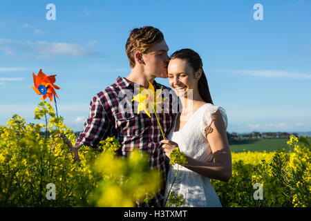 Man kissing on woman forehead in mustard field Stock Photo