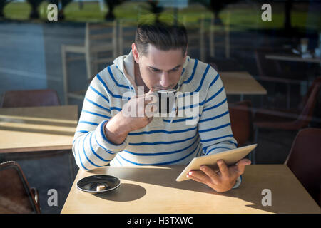 Man using digital tablet while having coffee Stock Photo