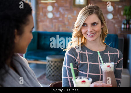 Female friends interacting with each other while having coffee Stock Photo