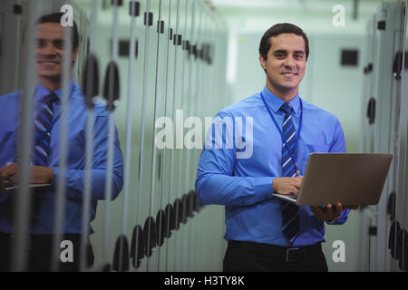Portrait of technician using laptop while analyzing server Stock Photo