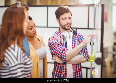 Confident executive pointing on whiteboard to colleagues at creative office Stock Photo