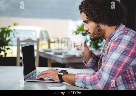Man using laptop while having coffee Stock Photo