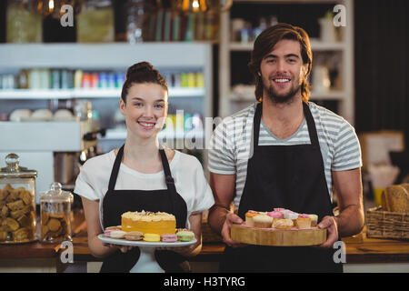 Portrait of waiter and waitress holding a tray of cupcakes Stock Photo