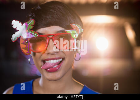 Woman wearing fancy sunglasses making funny faces in bar Stock Photo