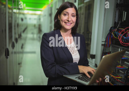 Technician using laptop while analyzing server Stock Photo