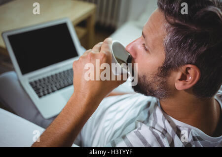 Man having coffee while using laptop Stock Photo