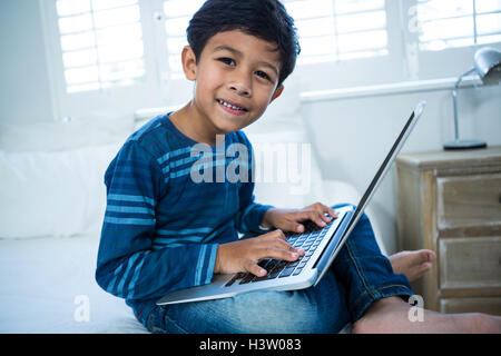 Boy using laptop while relaxing on bed Stock Photo
