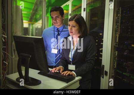Technicians working on personal computer while analyzing server Stock Photo