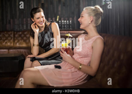 Female friends interacting with each other while having cocktail Stock Photo