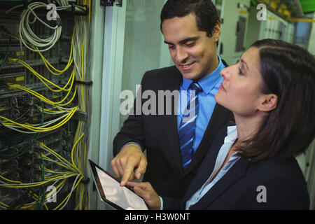 Technicians using digital tablet while analyzing server Stock Photo