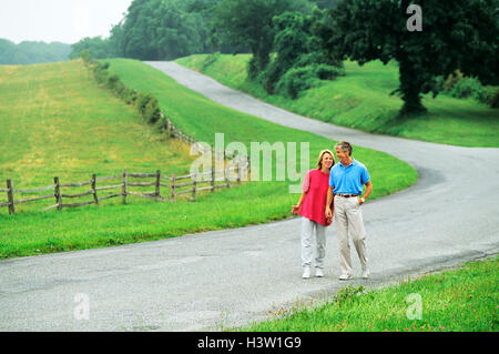 Couple walking down country road Stock Photo - Alamy
