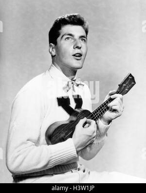 1940s 1950s COLLEGE BOY WEARING X LETTER SWEATER SINGING AND PLAYING UKULELE Stock Photo