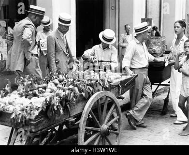 1930s 1940s MEN IN STRAW HATS SIDEWALK AND APPLE VENDOR WITH CART HAVANA CUBA Stock Photo