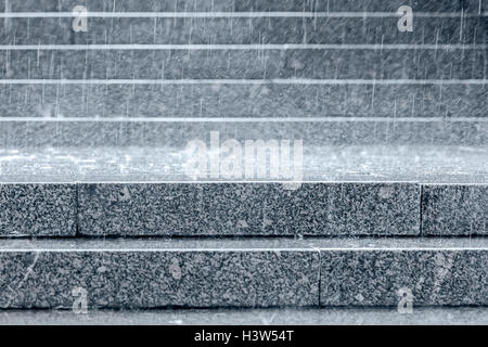 granite steps of staircase with raindrops falling on them during heavy rain Stock Photo