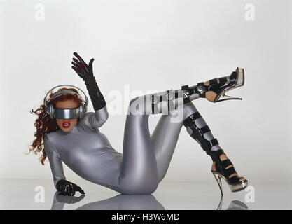 Woman, young, clothes, silver, futuristic, stilettos, data glasses, lie, gesture, Future, studio, inside, sit, cyberspace, fashion, overall, shoes, Highheels, gloves, long-haired, red, long-haired, red-haired, make-up, modern, future, monitor glasses, eye Stock Photo