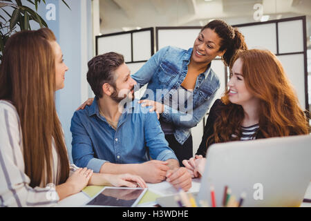 Businessman with happy female coworkers at desk Stock Photo