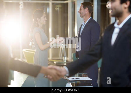 Businessmen shaking hands with colleagues Stock Photo