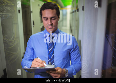 Technician maintaining record of rack mounted server on clipboard Stock Photo