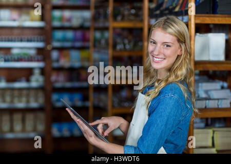 Smiling female staff using digital tablet in supermarket Stock Photo