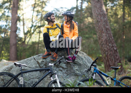 Biker couple sitting on rock and interacting with each other Stock Photo