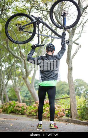 Male cyclist carrying mountain bike Stock Photo