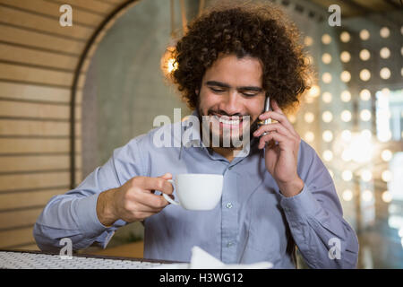 Man talking on mobile phone while having cup of tea Stock Photo