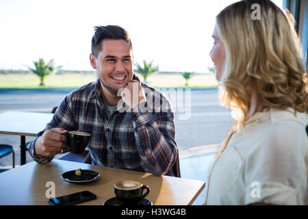 Smiling couple interacting with each other while having cup of coffee Stock Photo