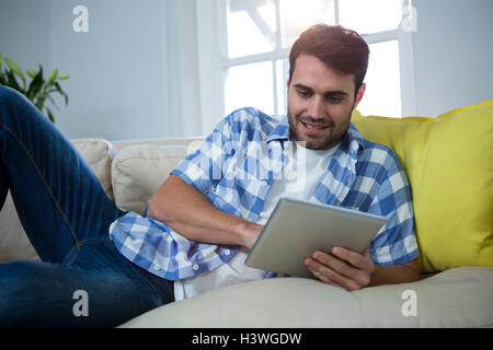 Man using digital tablet while relaxing on sofa Stock Photo