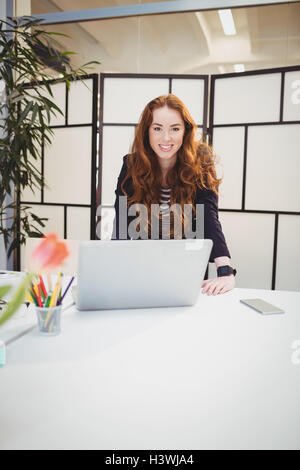 Portrait of confident businesswoman standing in meeting room at creative office Stock Photo