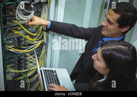 Technicians using laptop while analyzing server Stock Photo