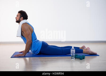 Man doing cobra pose on exercise mat Stock Photo