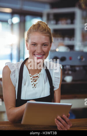 Portrait of waitress standing at counter using digital tablet Stock Photo