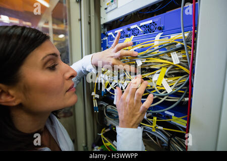 Technician checking cables in a rack mounted server Stock Photo