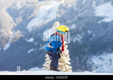 Cute little boy, skiing happily in Austrian ski resort in the mountains, wintertime Stock Photo