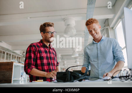 Shot of happy young man working together in modern office. Team of developers working on testing new virtual reality technology. Stock Photo