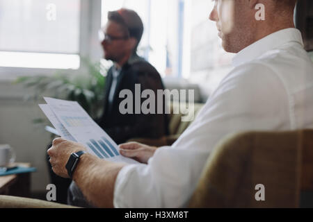 Shot of business people sitting in office and going through business reports. Businessman reading charts during meeting. Stock Photo